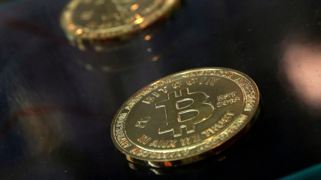 In this Dec. 8, 2017, file photo, coins are displayed next to a Bitcoin ATM in Hong Kong. (AP Photo/Kin Cheung, File)